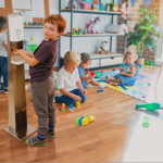 A boy sanitizing hands by floor stand automatic hand sani tiser dispenser